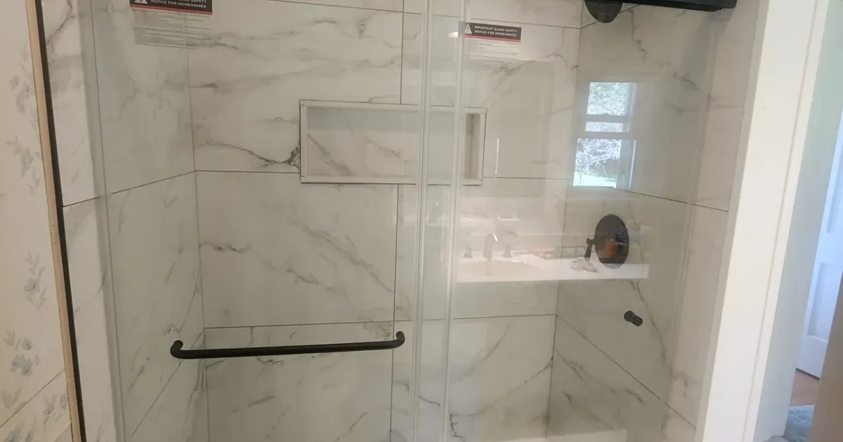 Completed Rochester-area glass shower with marble-look tile and black hardware