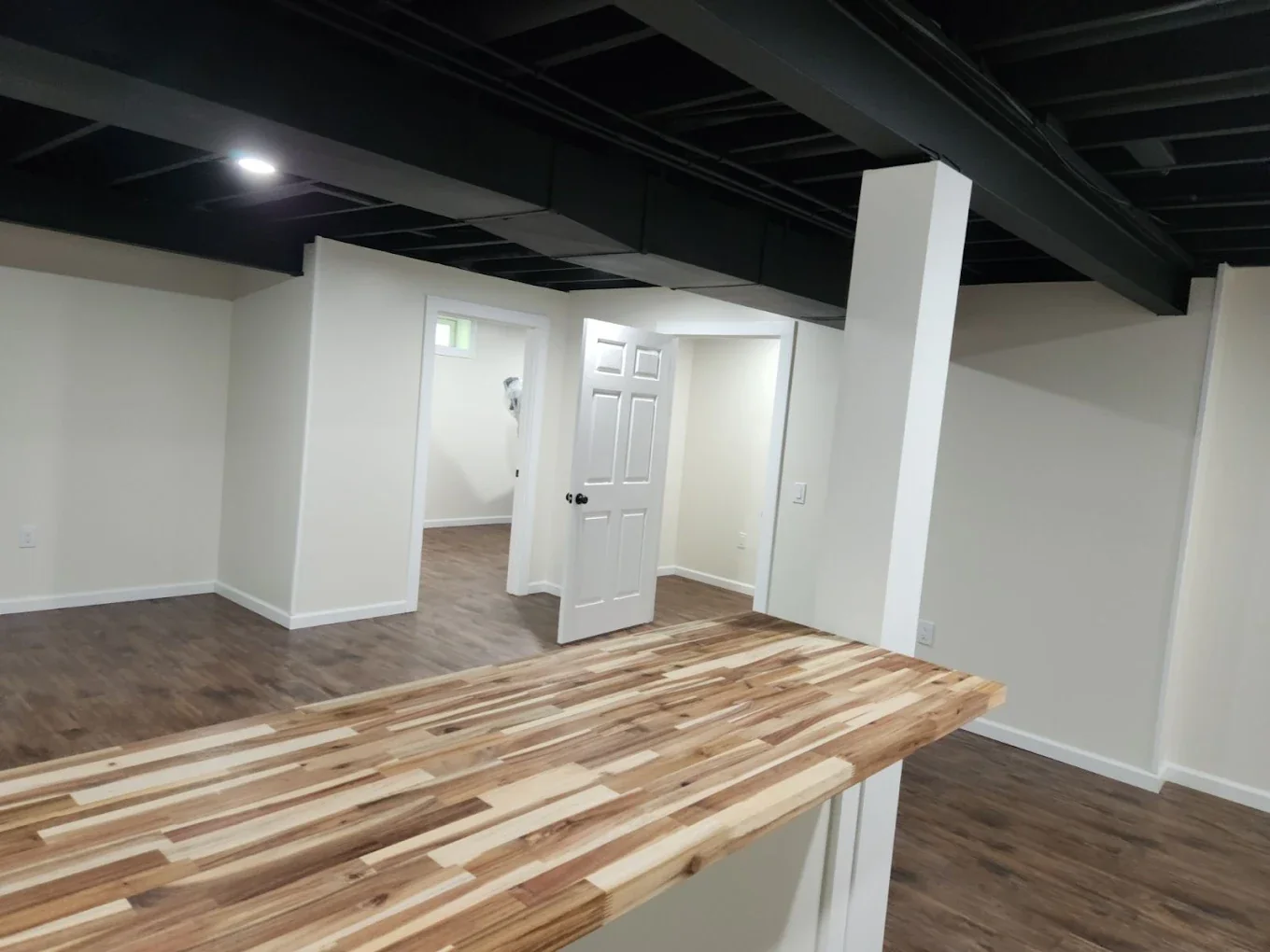 Finished basement with wood bar and dark open ceiling